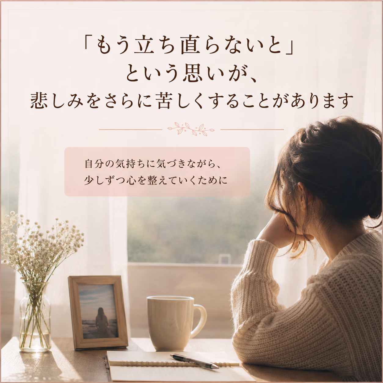 Softly lit desk scene: a woman in a cream sweater rests her head on her hand beside a mug, photo frame, and dried flowers, with Japanese text about acknowledging feelings and slowly easing the heart.